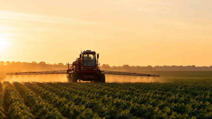 Pulverizadora agrícola aplicando fitosanitarios sobre un cultivo de soja al amanecer, con luz dorada y paisaje rural argentino de fondo, sin presencia de personas.