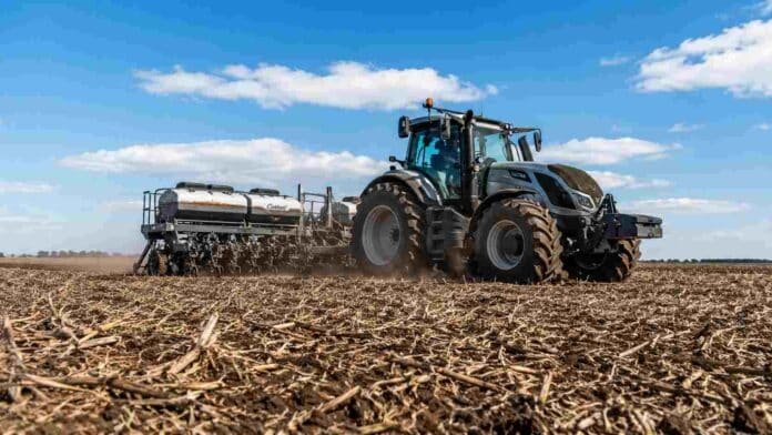 Tractor con sembradora trabajando en un campo húmedo con rastrojo de soja durante la siembra de cebada en la pampa húmeda.