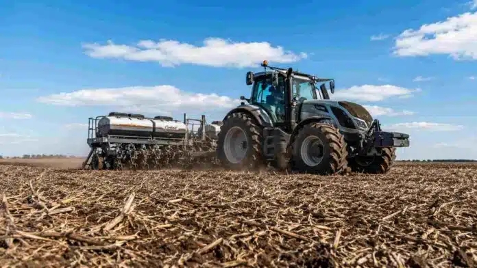 Tractor con sembradora trabajando en un campo húmedo con rastrojo de soja durante la siembra de cebada en la pampa húmeda.