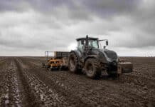 Cinco semanas sin lluvia importante y de repente 85 mm en el oeste: así el clima le devolvió el trigo a la región núcleo Tractor Valtra HiTech con sembradora de granos finos trabajando sobre un lote húmedo de la región pampeana, con suelo oscuro recién sembrado y cielo nublado de invierno.