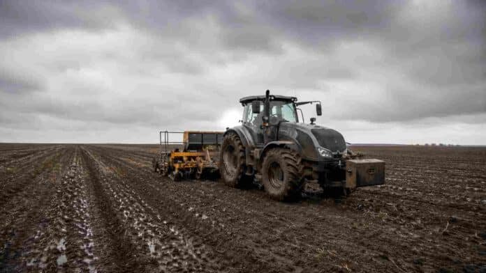 siembra-de-granos-finos-en-suelo-humedo-tras-las-lluvias Tractor Valtra HiTech con sembradora de granos finos trabajando sobre un lote húmedo de la región pampeana, con suelo oscuro recién sembrado y cielo nublado de invierno.