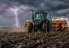 La siembra de trigo alcanza el 65,8% del área prevista, pero persisten demoras por el exceso de humedad Tractor con sembradora trabajando sobre suelo húmedo con rastrojo bajo cielo de tormenta y un relámpago en el horizonte.