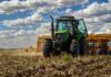 La siembra de trigo avanza a ritmo récord, pero los precios caen por la presión global Tractor verde con sembradora trabajando sobre rastrojo en un lote agrícola argentino, bajo cielo con nubes y colores vívidos durante la siembra de trigo.