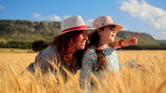 Madre e hija observan un cultivo de trigo en un campo argentino, representando la producción sustentable de alimentos y el cuidado de los recursos naturales