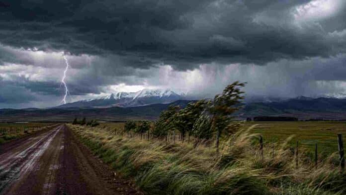 alerta-tormentas-viento-nieve-ruralnet Tormenta intensa con rayos, lluvias y fuertes ráfagas sobre un campo rural, con montañas nevadas en el horizonte.