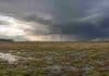 El agro enfrenta tres días de tormentas, heladas y lluvias Campo agrícola argentino con rastrojo húmedo y charcos bajo nubes de tormenta y cortinas de lluvia