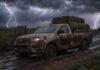 Heladas, neblinas y lluvias aisladas complicarán al campo en los próximos días Camioneta cabina simple cargada con fardos de pasto avanza por un camino rural embarrado bajo lluvia intensa y relámpagos.