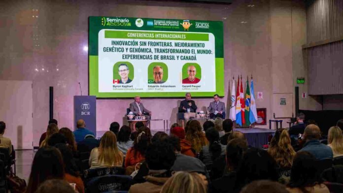 Auditorio con asistentes durante una conferencia internacional sobre mejoramiento genético y genómica aplicada a la producción animal, con panel de especialistas en el escenario y pantalla de presentación al fondo.