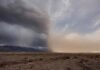 El SMN activa alertas por lluvia, viento fuerte, nieve y zonda en siete provincias Paisaje rural argentino con contraste climático: tormenta con lluvia sobre cerros cordilleranos de un lado y viento levantando tierra seca sobre una llanura árida del otro.