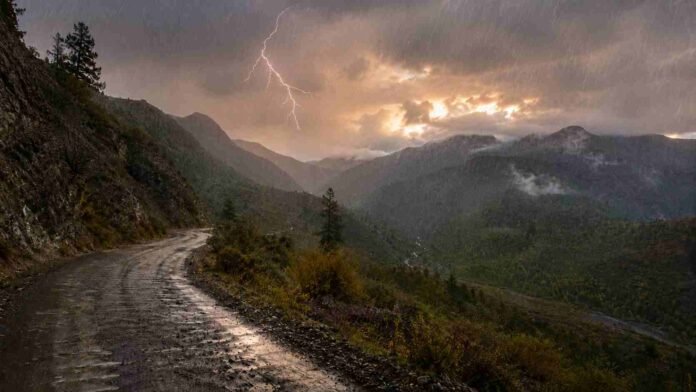 cordillera-neuquen-rio-negro-lluvia-relampago-ruralnet Camino de montaña húmedo en la cordillera de Neuquén o Río Negro, con lluvia ligera, un relámpago y claros de cielo entre las nubes al atardecer