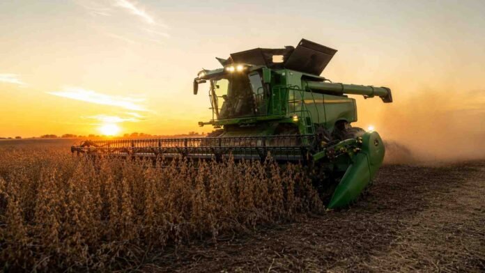 Cosechadora John Deere S7 cosechando soja al atardecer en un campo de la pampa húmeda, con luz dorada y polvo en suspensión.