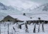 El SMN activa alerta amarilla por nevadas en la cordillera patagónica Casco de estancia patagónica cubierto de nieve, con alambrados nevados y la cordillera de fondo bajo un cielo encapotado.