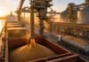 Las exportaciones de granos marcaron un récord histórico en el primer semestre de 2026 Buque granelero cargando granos en una terminal portuaria argentina, con silos, cintas transportadoras y camión cerealero durante una operación de exportación.