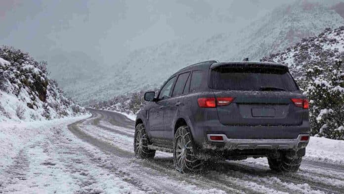 Vehículo 4x4 con cadenas en las ruedas circula bajo la nieve por un camino cordillerano de la Patagonia argentina.