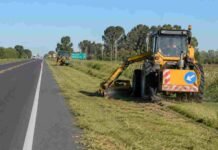 El Gobierno licitó 9.000 km de rutas pero solo construirá 300 km de autopistas: el interior del país esperaba mucho más Maquinaria vial realizando tareas de mantenimiento y corte de pasto en la banquina de una ruta nacional argentina, con tránsito y campos rurales de fondo.