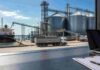 Granos: China compró 300.000 toneladas de soja estadounidense y el mercado entero subió: la señal que todos esperaban Terminal portuaria de granos con silos, camiones y buque de carga, vista desde una oficina de operaciones del mercado granario.