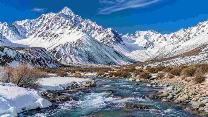 nevadas-cordillera-reservas-agua-el-nino-ruralnet Cordillera de los Andes cubierta de nieve y un río de deshielo en primer plano, imagen vinculada con la recarga de reservas de agua durante años El Niño.