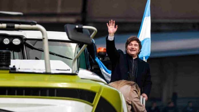 presidente-acto-rural-palermo-ruralnet Un mandatario saluda junto a maquinaria agrícola y una bandera argentina durante un acto en la Exposición Rural de Palermo.
