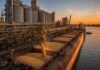 La soja lideró el mercado físico de Rosario en la víspera del feriado Puerto cerealero sobre el río Paraná en Rosario, con silos y cinta transportadora cargando granos en un buque al atardecer.
