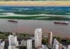 Rosario presentó la Conferencia Mundial de Investigación en Soja 2027 Vista aérea de la ciudad de Rosario y el río Paraná, con buques navegando frente a la costa y las islas del delta al fondo.