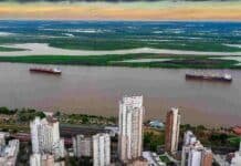 Rosario presentó la Conferencia Mundial de Investigación en Soja 2027 Vista aérea de la ciudad de Rosario y el río Paraná, con buques navegando frente a la costa y las islas del delta al fondo.