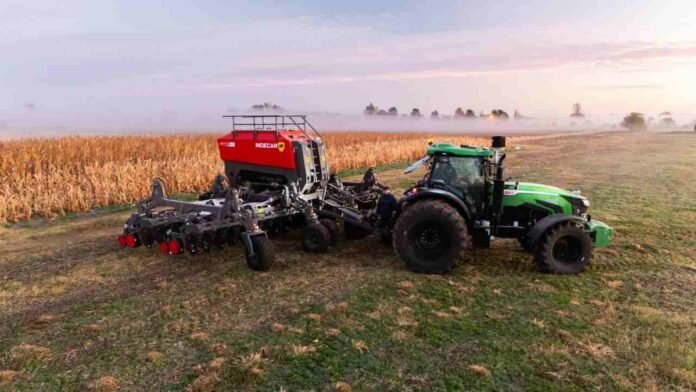 sembradora-tractor-siembra-directa-ruralnet Tractor con sembradora de siembra directa trabajando junto a un lote de maíz en un campo argentino al amanecer con neblina.