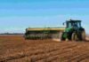 La siembra de trigo entra en su tramo final con 100.000 hectáreas aún en duda Tractor con sembradora trabajando en un lote agrícola durante la siembra de trigo, con suelo preparado y cielo despejado.
