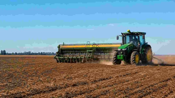 siembra-trigo-campo-argentino-ruralnet Tractor con sembradora trabajando en un lote agrícola durante la siembra de trigo, con suelo preparado y cielo despejado.