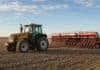 La siembra de trigo alcanzó el 98,4% y las lluvias frenan el avance en el sudeste bonaerense Tractor Valtra HiTech amarillo con una sembradora roja durante la siembra de trigo en un campo argentino.
