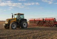 La siembra de trigo alcanzó el 98,4% y las lluvias frenan el avance en el sudeste bonaerense Tractor Valtra HiTech amarillo con una sembradora roja durante la siembra de trigo en un campo argentino.