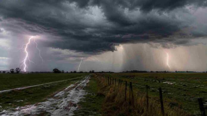 tormenta-campo-rayos-lluvia-ruralnet Tormenta intensa en medio de un campo, con cielo oscuro, rayos visibles, fuerte cortina de lluvia y camino rural embarrado.