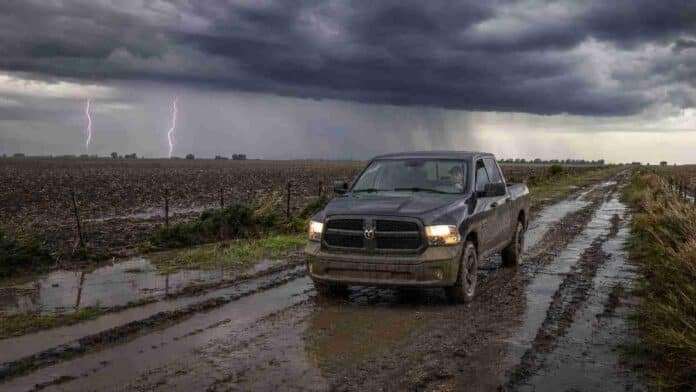Camioneta 4x4 circula por un camino rural embarrado mientras una fuerte tormenta con relámpagos avanza sobre la Pampa Húmeda