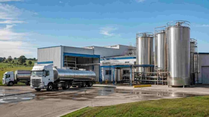 fabrica-industria-lactea-argentina Planta industrial láctea con tanques de acero inoxidable y camiones cisterna para la recepción y procesamiento de leche.