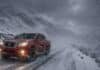 Se intensifican las nevadas: hasta 50 cm, ráfagas de más de 100 km/h y alertas en 11 provincias Pickup 4x4 roja con cadenas en los neumáticos circulando por una ruta de montaña nevada en la cordillera patagónica, con viento blanco y baja visibilidad.