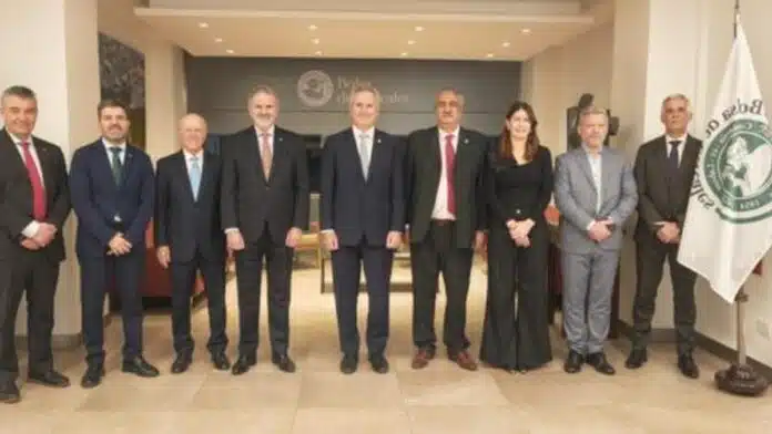 Autoridades y representantes del sector agropecuario posan durante una reunión institucional, junto a las banderas de Argentina y de una entidad rural
