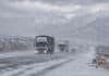 El SMN renueva el alerta por nevadas y suma viento fuerte en Cuyo y Patagonia Camiones y vehículos circulan por una ruta nevada de Mendoza bajo viento blanco, con la cordillera de los Andes cubierta de nieve al fondo.
