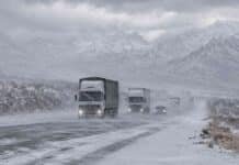 El SMN renueva el alerta por nevadas y suma viento fuerte en Cuyo y Patagonia Camiones y vehículos circulan por una ruta nevada de Mendoza bajo viento blanco, con la cordillera de los Andes cubierta de nieve al fondo.