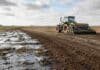 La siembra de cebada llega al 94,7% pese a la falta de piso en el sur Tractor sembrando cebada en un lote con exceso de humedad y sectores encharcados, una escena que refleja la demora de la campaña en los núcleos cebaderos del sur de Argentina.