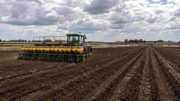 siembra-girasol-campana-2026-27 Tractor con sembradora trabajando en un lote destinado a girasol durante la campaña 2026/27, con suelo húmedo y cielo nublado.