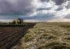 Maíz: adelantan la siembra para escapar al “Niño” Tractor sembrando maíz en la Región Núcleo junto a un lote de trigo afectado por granizo, bajo un cielo de tormenta.