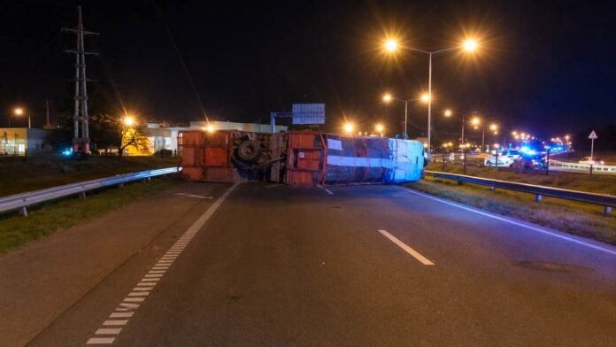 vuelco-camion-jaula-ruta Camión jaula volcado sobre una ruta durante la noche, con presencia de vehículos de emergencia en el lugar.
