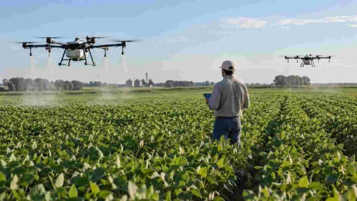 drones-agricolas-aplicacion-cultivos Drones agrícolas realizan aplicaciones sobre un cultivo mientras un operario supervisa el trabajo en el lote.