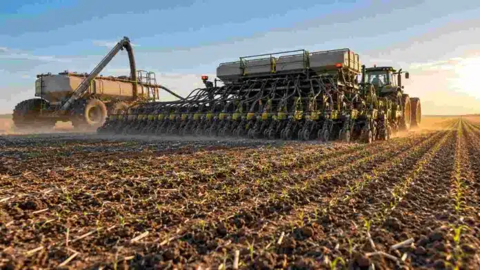 inversion-agricola-siembra-maiz-insumos-campo Sembradora de gran porte y carro de insumos trabajando en la implantación de un cultivo, en una escena que representa la inversión agrícola de la campaña 2025/26.