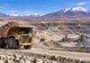 Minería argentina: récord de exportaciones e inversión en 2026 Camión minero de gran porte operando en una explotación a cielo abierto en la cordillera argentina, con instalaciones de procesamiento al fondo.