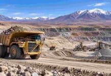 Minería argentina: récord de exportaciones e inversión en 2026 Camión minero de gran porte operando en una explotación a cielo abierto en la cordillera argentina, con instalaciones de procesamiento al fondo.