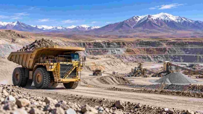 mineria-argentina-camion-cantera Camión minero de gran porte operando en una explotación a cielo abierto en la cordillera argentina, con instalaciones de procesamiento al fondo.