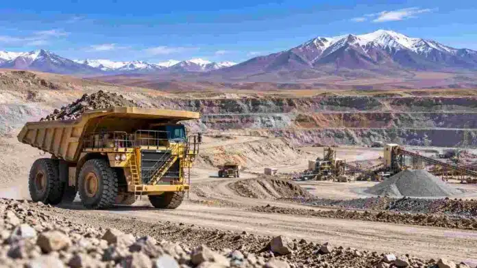 mineria-argentina-camion-cantera Camión minero de gran porte operando en una explotación a cielo abierto en la cordillera argentina, con instalaciones de procesamiento al fondo.