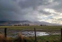 Pronóstico agropecuario: tormentas fuertes el jueves y posibles nevadas el sábado en Buenos Aires Campo húmedo con charcos bajo un cielo de tormenta y sierras con nieve, por el pronóstico agropecuario para Buenos Aires.