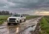 Pronóstico para martes, miércoles y jueves: las lluvias pierden fuerza y octubre comienza con mejoras Camioneta atraviesa un charco en un camino rural bajo la lluvia, entre campos verdes y nubes con claros en el horizonte.