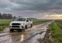Pronóstico para martes, miércoles y jueves: las lluvias pierden fuerza y octubre comienza con mejoras Camioneta atraviesa un charco en un camino rural bajo la lluvia, entre campos verdes y nubes con claros en el horizonte.